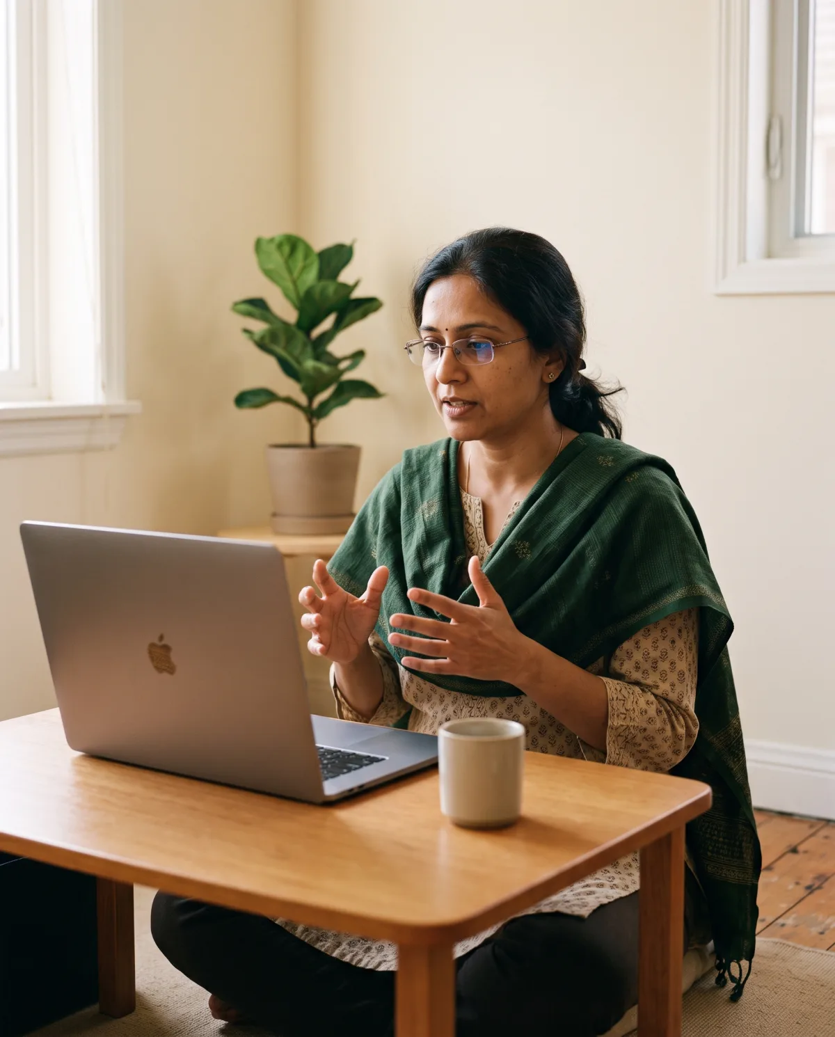 A practitioner at a laptop, mid-sentence in a live session